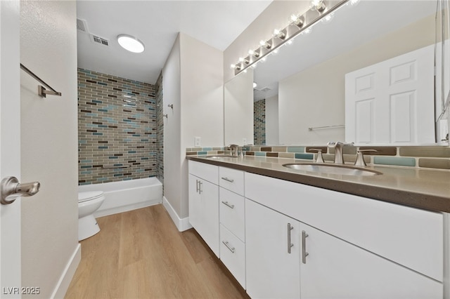 full bathroom featuring hardwood / wood-style flooring, vanity, toilet, and tiled shower / bath combo