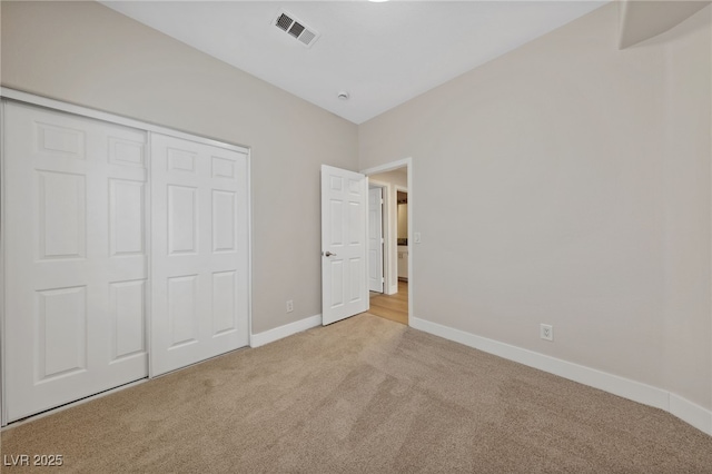 unfurnished bedroom featuring light carpet and a closet