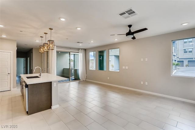 kitchen with light tile patterned floors, sink, ceiling fan, an island with sink, and decorative light fixtures