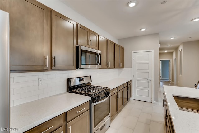 kitchen featuring light stone counters, stainless steel appliances, and tasteful backsplash