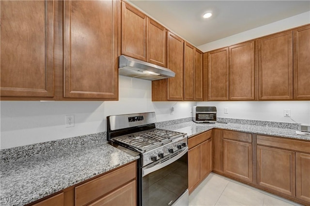 kitchen with light tile patterned flooring, light stone countertops, and stainless steel gas stove