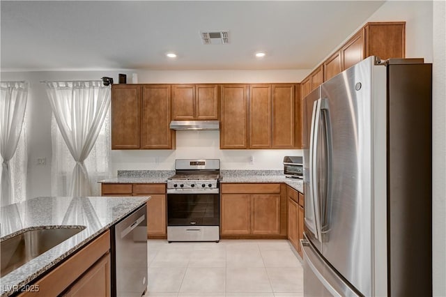 kitchen featuring light stone counters, appliances with stainless steel finishes, light tile patterned flooring, and sink