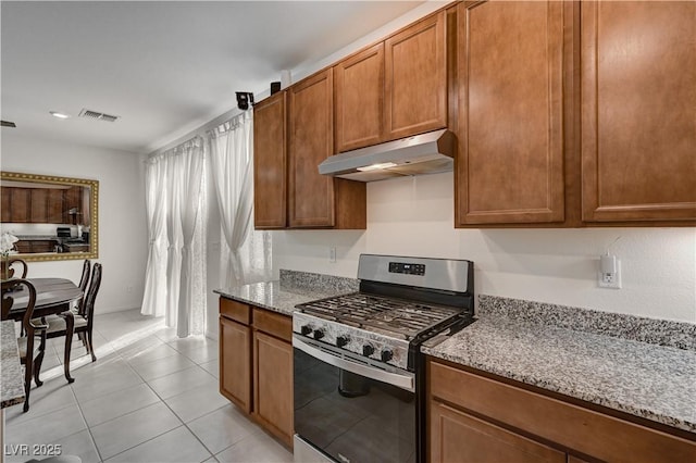 kitchen featuring gas stove, light tile patterned floors, and light stone counters