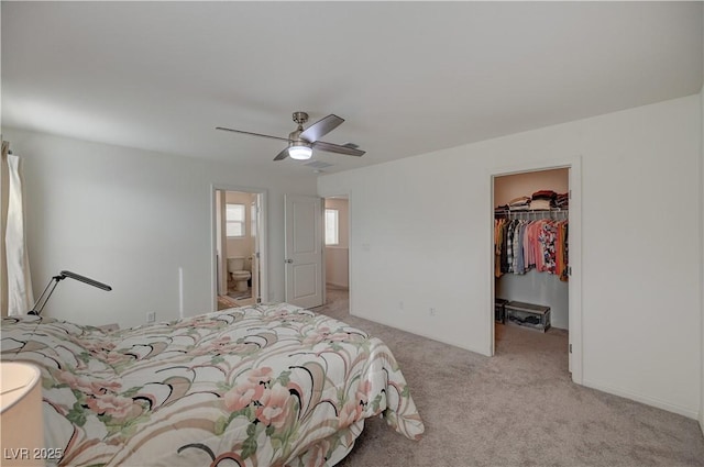 carpeted bedroom featuring a spacious closet, connected bathroom, ceiling fan, and a closet