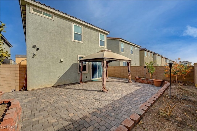 rear view of property featuring a gazebo and a patio