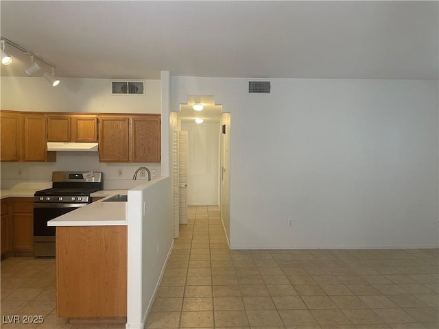 kitchen featuring stainless steel gas range oven, sink, and light tile patterned floors