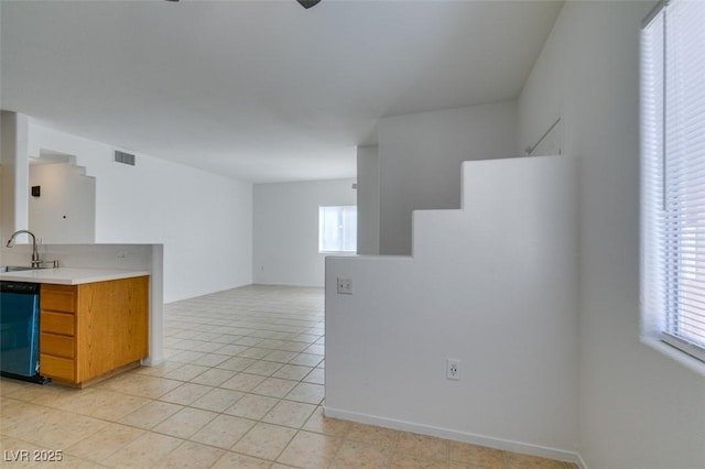 kitchen with sink, light tile patterned floors, and dishwashing machine