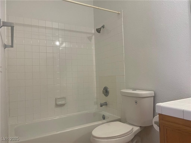 full bathroom with tiled shower / bath, vanity, and toilet