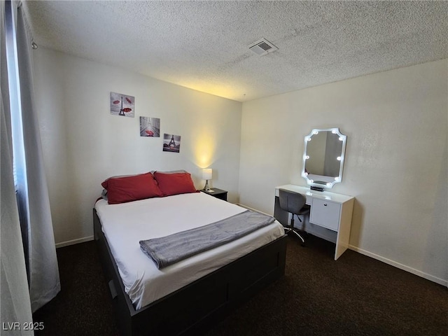 bedroom featuring a textured ceiling and dark colored carpet