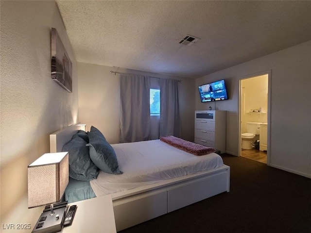 bedroom featuring ensuite bath and a textured ceiling