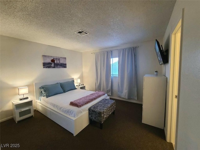 bedroom with dark colored carpet and a textured ceiling