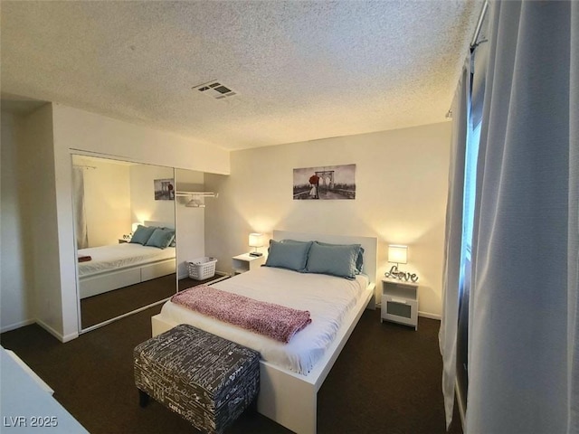 bedroom featuring a closet, dark carpet, and a textured ceiling