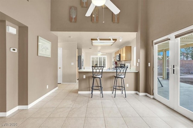 kitchen featuring french doors, a breakfast bar area, kitchen peninsula, ceiling fan, and stainless steel appliances