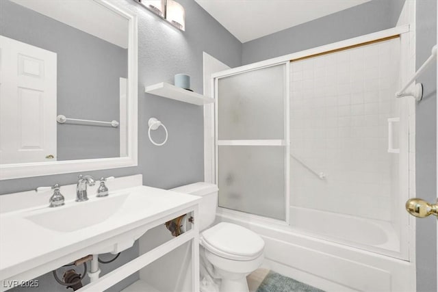 full bathroom with sink, shower / bath combination with glass door, and toilet