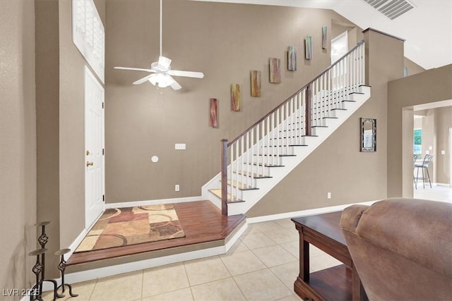 entryway featuring light tile patterned flooring, a towering ceiling, and ceiling fan