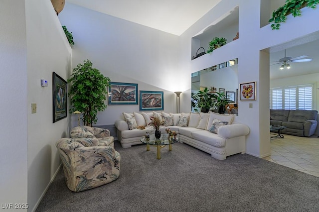 tiled living area featuring baseboards, carpet, a towering ceiling, and a ceiling fan