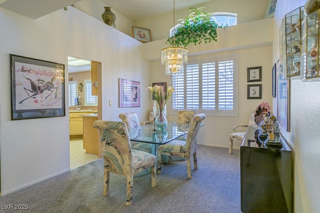 dining room with a notable chandelier, a high ceiling, baseboards, and light colored carpet