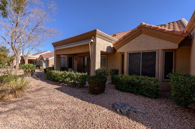 rear view of property with a tiled roof and stucco siding