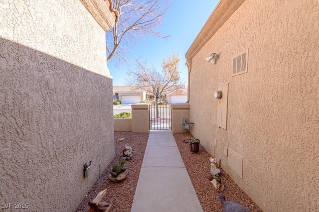 view of side of home with a gate and stucco siding