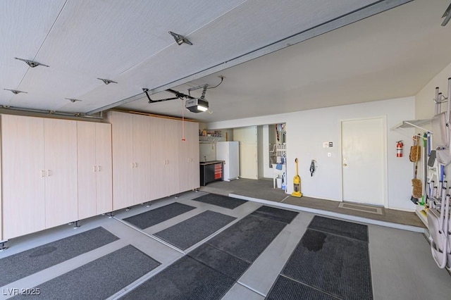 garage featuring freestanding refrigerator and a garage door opener