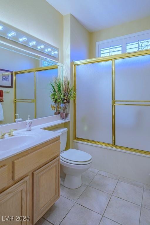 bathroom featuring tile patterned flooring, shower / bath combination with glass door, vanity, and toilet