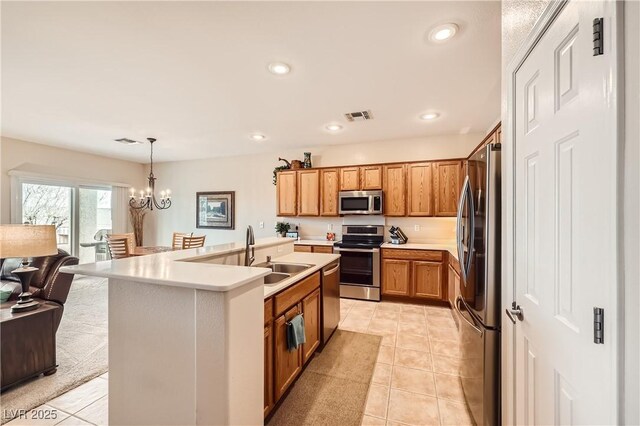 kitchen featuring sink, a chandelier, a center island with sink, appliances with stainless steel finishes, and pendant lighting