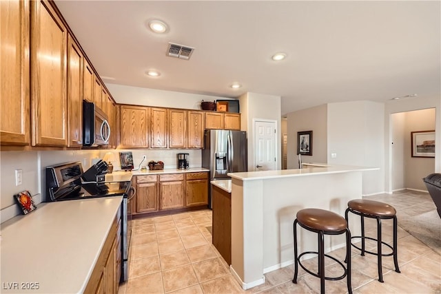 kitchen featuring stainless steel appliances, a center island, light tile patterned floors, and a kitchen breakfast bar