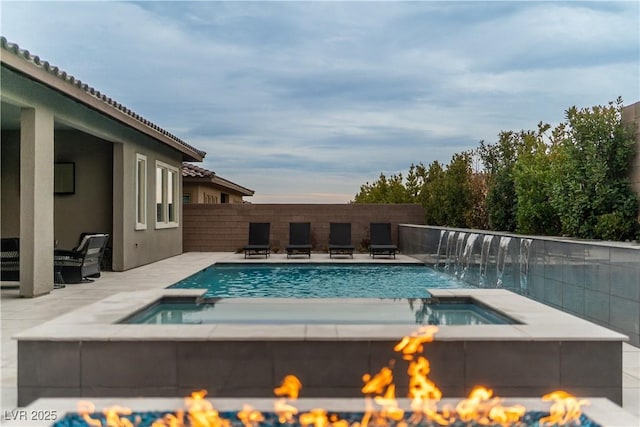 view of swimming pool with an in ground hot tub, pool water feature, a patio, and a fire pit