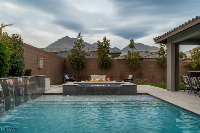 view of swimming pool featuring a patio, a mountain view, pool water feature, and an in ground hot tub