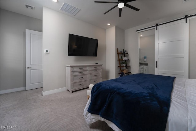 carpeted bedroom featuring connected bathroom, a barn door, and ceiling fan