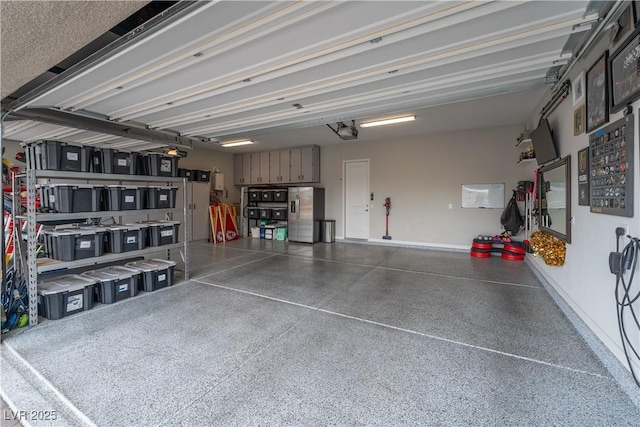 garage with stainless steel refrigerator with ice dispenser and a garage door opener