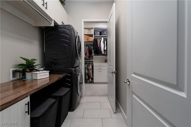 laundry area with cabinets, stacked washer / dryer, and light tile patterned floors