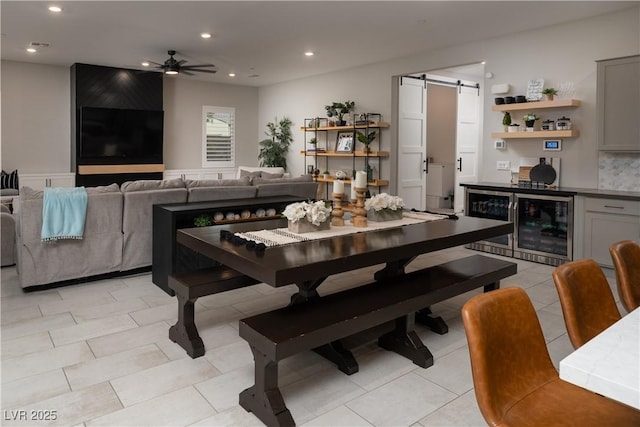 dining room featuring a barn door, light tile patterned floors, wine cooler, and ceiling fan