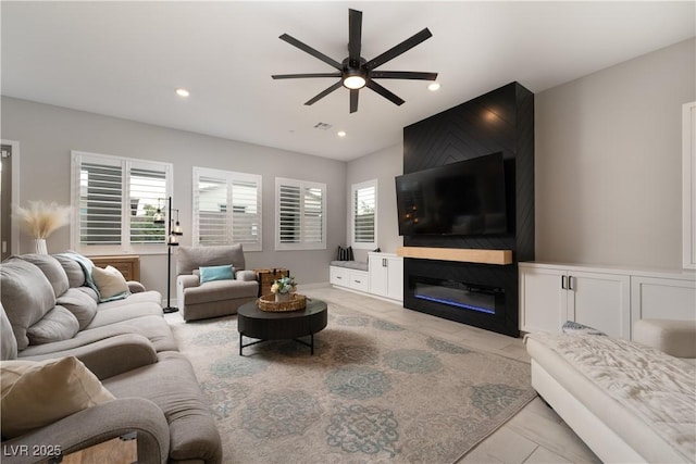 living room featuring a healthy amount of sunlight, a large fireplace, and ceiling fan