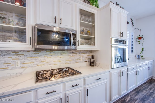 kitchen featuring light stone countertops, appliances with stainless steel finishes, white cabinets, and backsplash