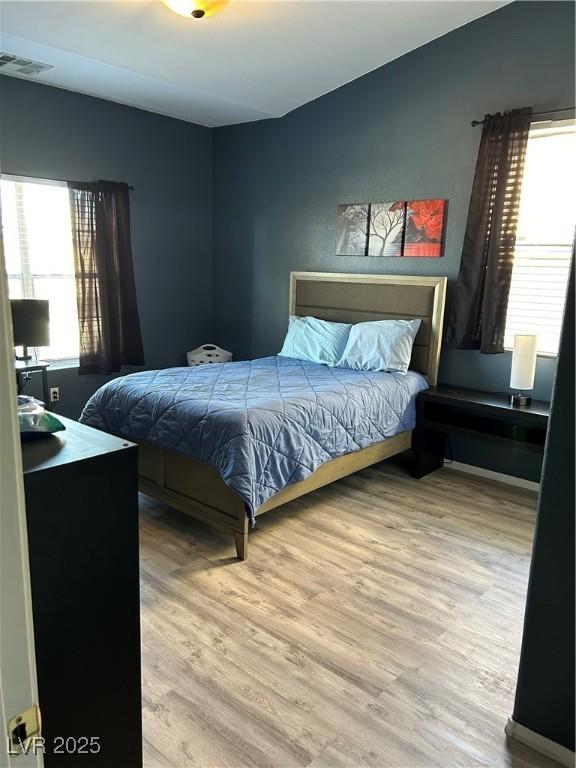 bedroom with hardwood / wood-style flooring and multiple windows