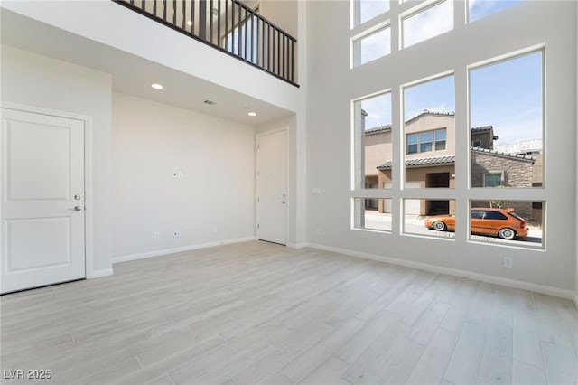 unfurnished room featuring a high ceiling and light wood-type flooring