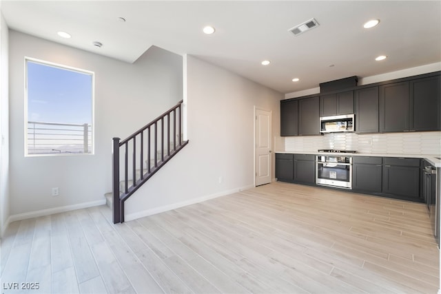 kitchen featuring stainless steel appliances, light hardwood / wood-style flooring, and decorative backsplash