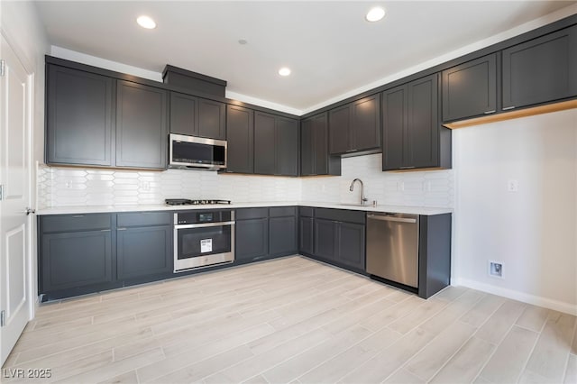 kitchen featuring tasteful backsplash, sink, light hardwood / wood-style floors, and appliances with stainless steel finishes