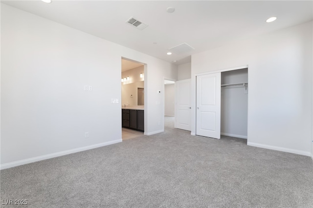 unfurnished bedroom with connected bathroom, light carpet, and a closet