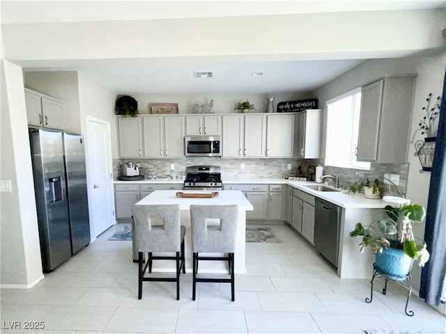 kitchen featuring a breakfast bar, sink, appliances with stainless steel finishes, a kitchen island, and decorative backsplash