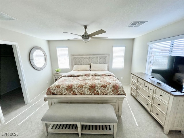 bedroom with ceiling fan, light colored carpet, and a textured ceiling