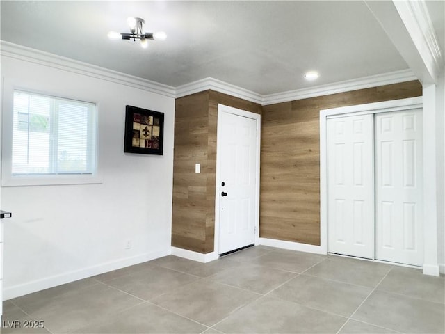 interior space featuring crown molding, a closet, light tile patterned floors, and wood walls