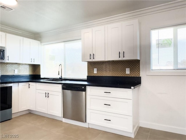 kitchen featuring light tile patterned flooring, tasteful backsplash, sink, white cabinets, and stainless steel appliances