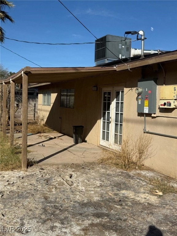 rear view of house featuring stucco siding, central AC, and french doors