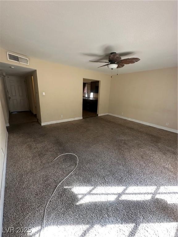 carpeted spare room with a ceiling fan, visible vents, and baseboards