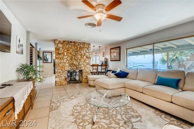 tiled living room with a stone fireplace and ceiling fan