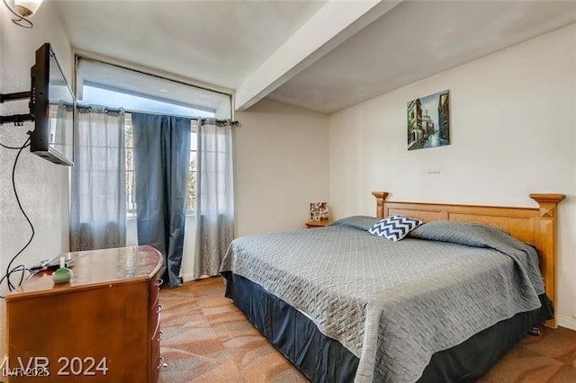 bedroom with beamed ceiling and light colored carpet