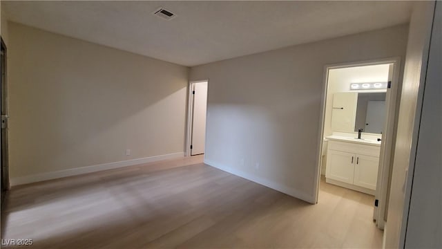 unfurnished bedroom featuring sink, connected bathroom, and light hardwood / wood-style floors