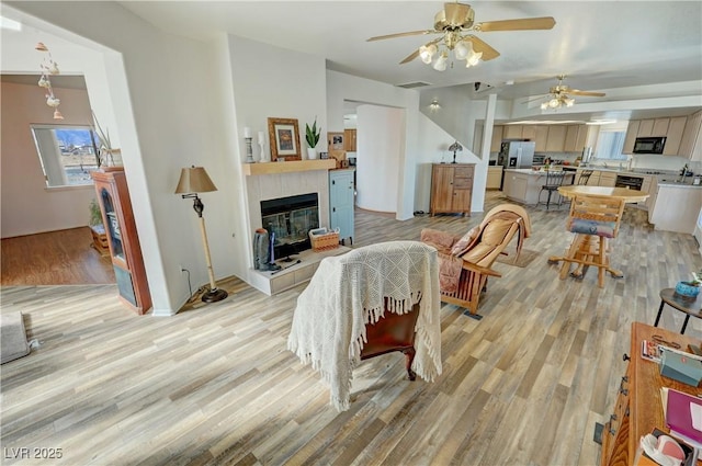 living room with a tile fireplace and light wood-type flooring